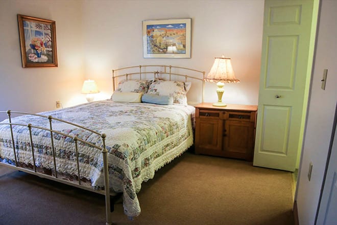 A cozy bedroom with a neatly made bed, bedside lamps, and warm decor.