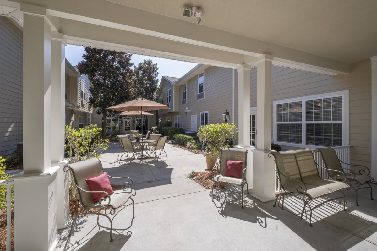 A cozy outdoor patio with seating arrangements and a sun umbrella, perfect for relaxing on a sunny day.