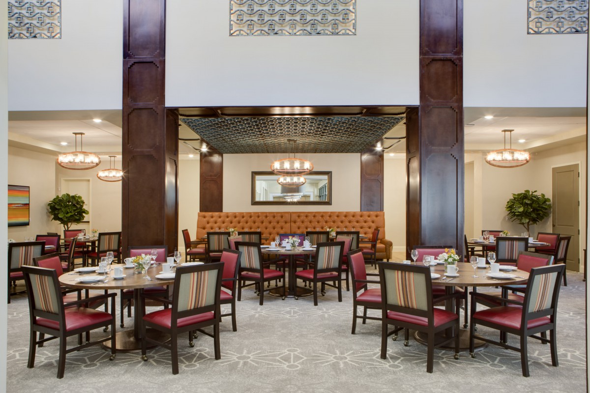A spacious and elegantly decorated dining room featuring multiple tables and chairs, with a warm and inviting ambiance.