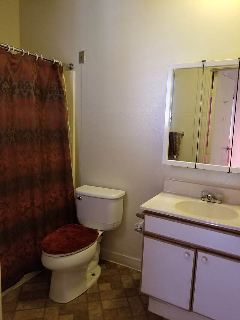 A simple bathroom with a toilet, sink, mirror, and shower curtain.