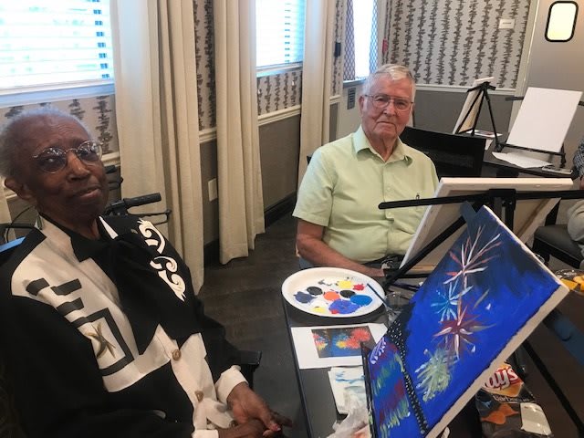 Two seniors enjoying a painting session together.