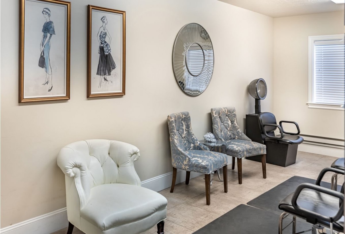 A cozy waiting room featuring stylish chairs, decorative wall art, and a mirror.