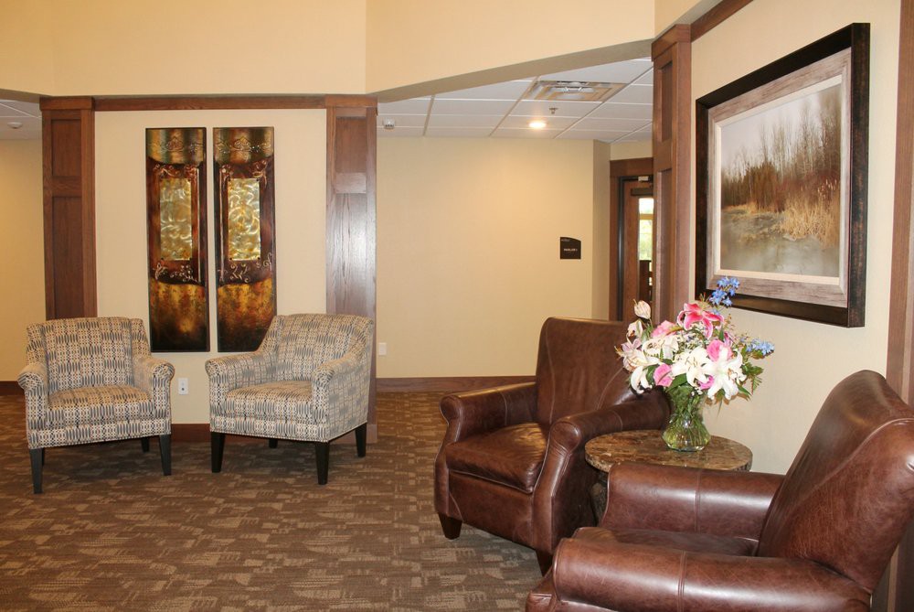 A cozy lobby area with armchairs, a painting, and a flower arrangement.