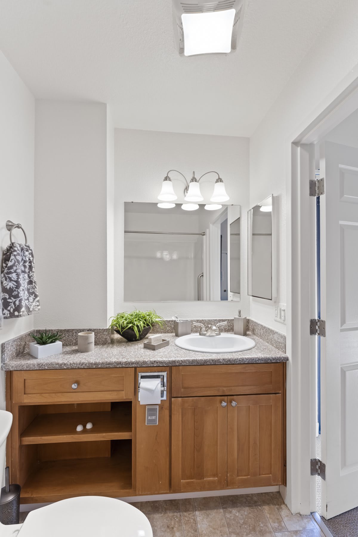 A modern bathroom with a wooden vanity, sink, and large mirror.