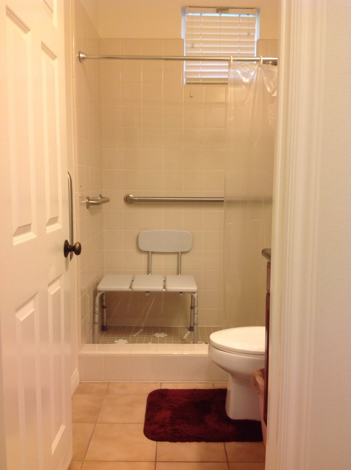 An accessible bathroom with a shower chair and grab bar.