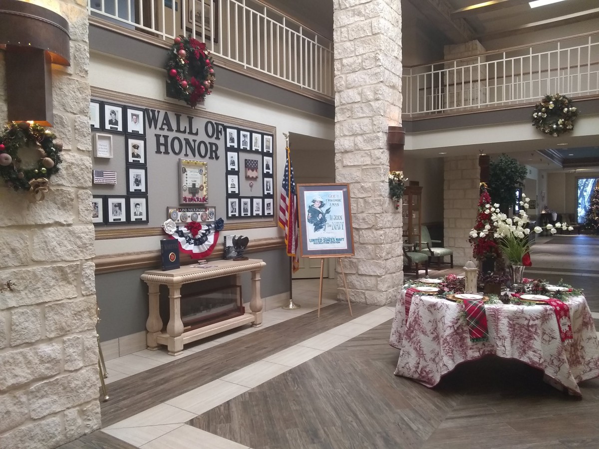 An indoor memorial display titled 'Hall of Honor' featuring photos, wreaths, and American flags.
