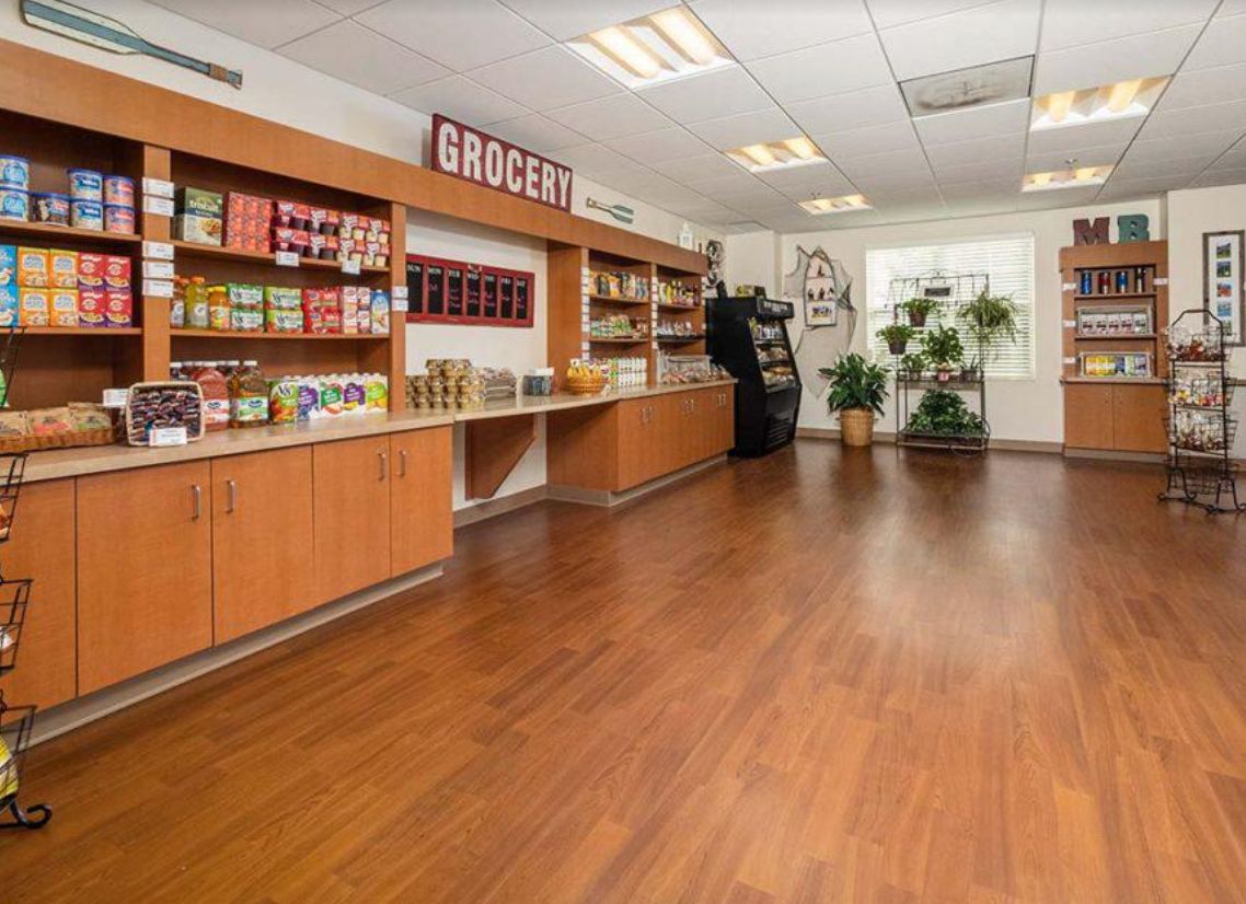 An organized grocery store interior with wooden floors and shelves stocked with various products.