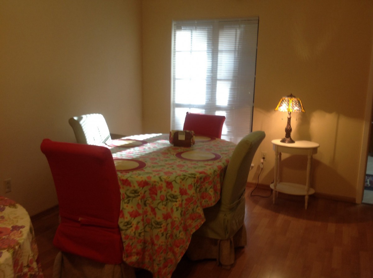 A cozy dining room with a floral tablecloth and a warm lamp.