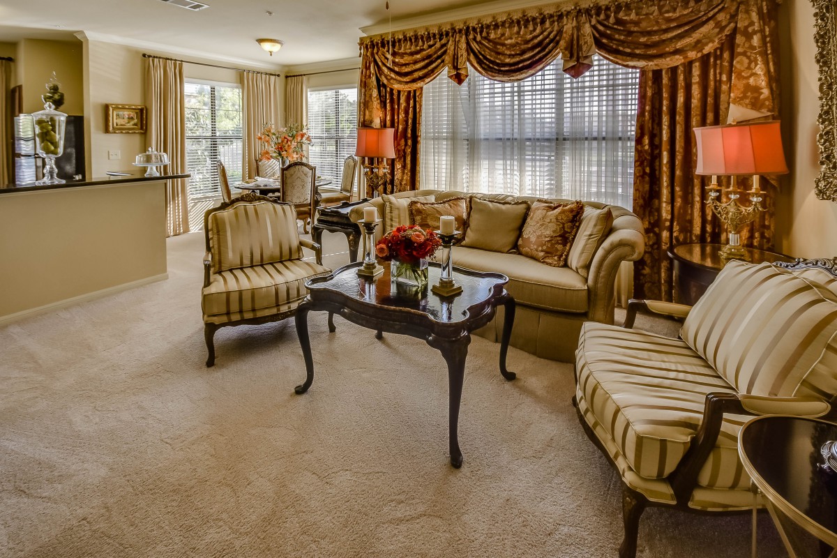 A traditional style living room with upholstered furniture, ornate curtains, and a cozy atmosphere.