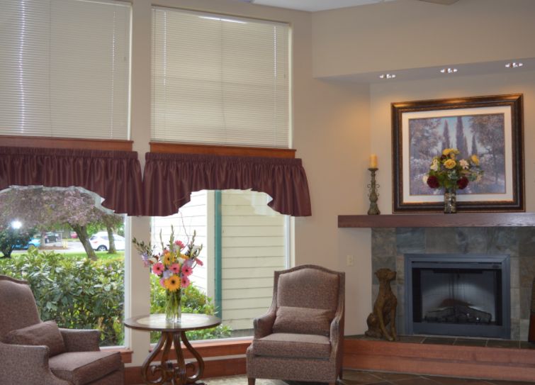 A cozy living room with elegant window treatments, comfortable armchairs, and a decorated fireplace.