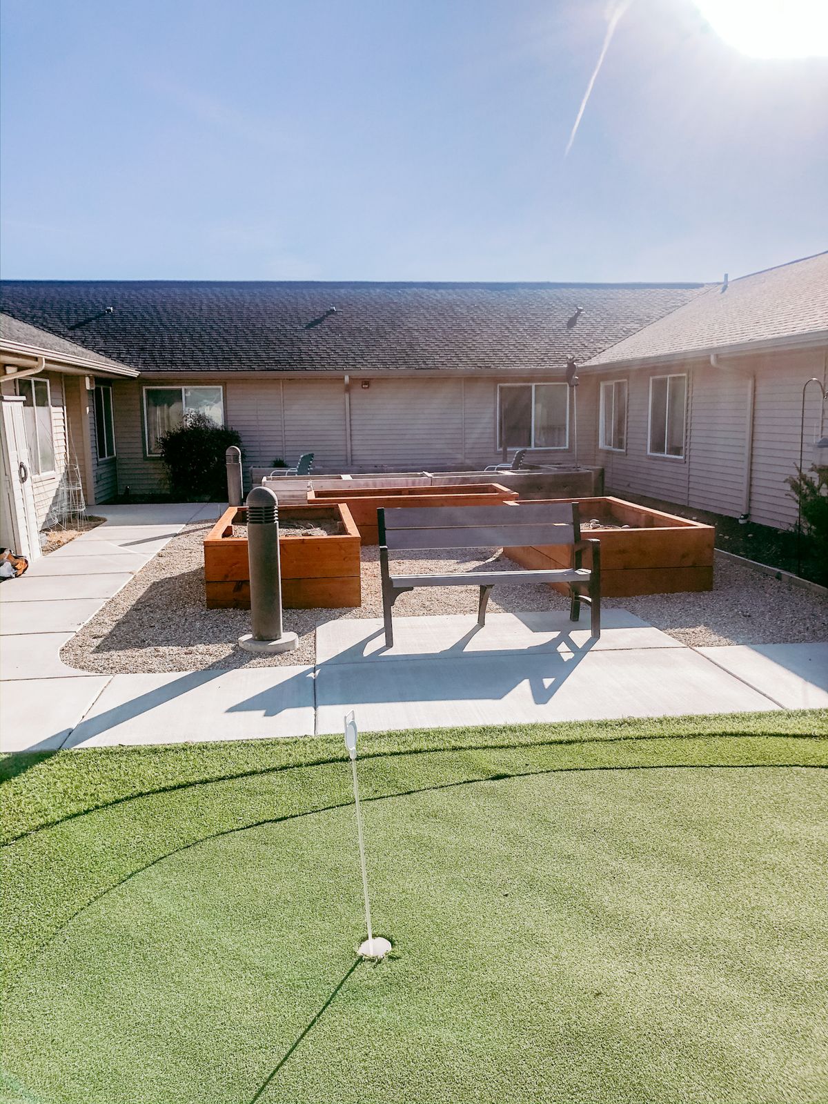A sunny courtyard features garden beds and a putting green, offering a relaxing outdoor space.
