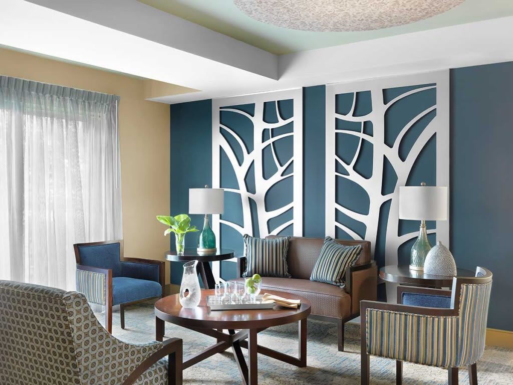 A modern living room features decorative wall panels with a nature-inspired design, complemented by stylish furniture and a blue and white color scheme.