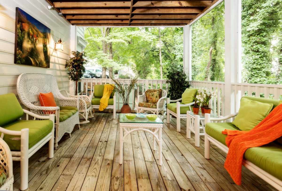 A cozy porch with vibrant seating and lush greenery.