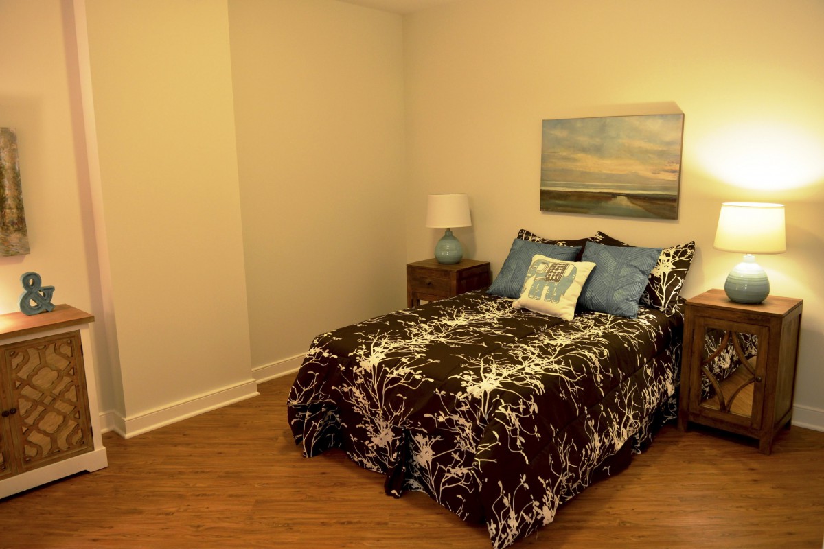 A cozy and modern bedroom featuring a bed with decorative pillows, a bedside lamp, and wall art.