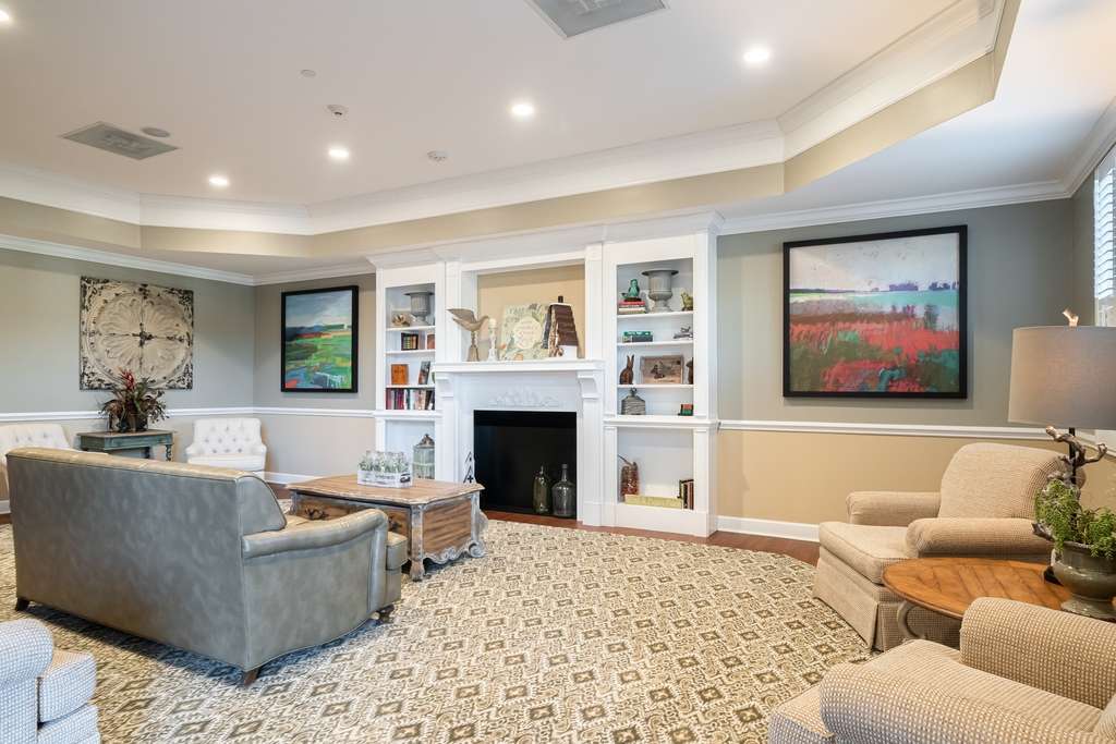 A cozy living room with a fireplace, surrounded by comfortable furniture, artwork, and built-in shelves.
