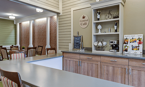 A cozy cafe interior with a wooden counter and decorative shelves, featuring a small seating area.