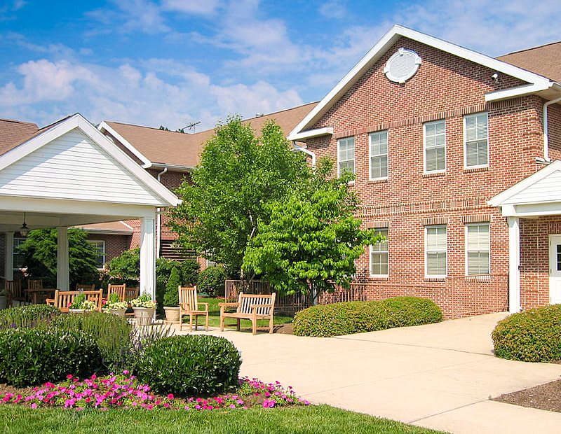 A brick residential building with a well-maintained garden and driveway.