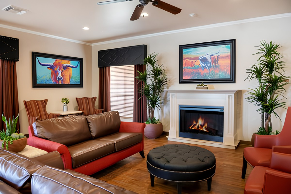 A cozy living room with a modern design, featuring a fireplace, colorful artwork, and a comfortable brown and red sofa.