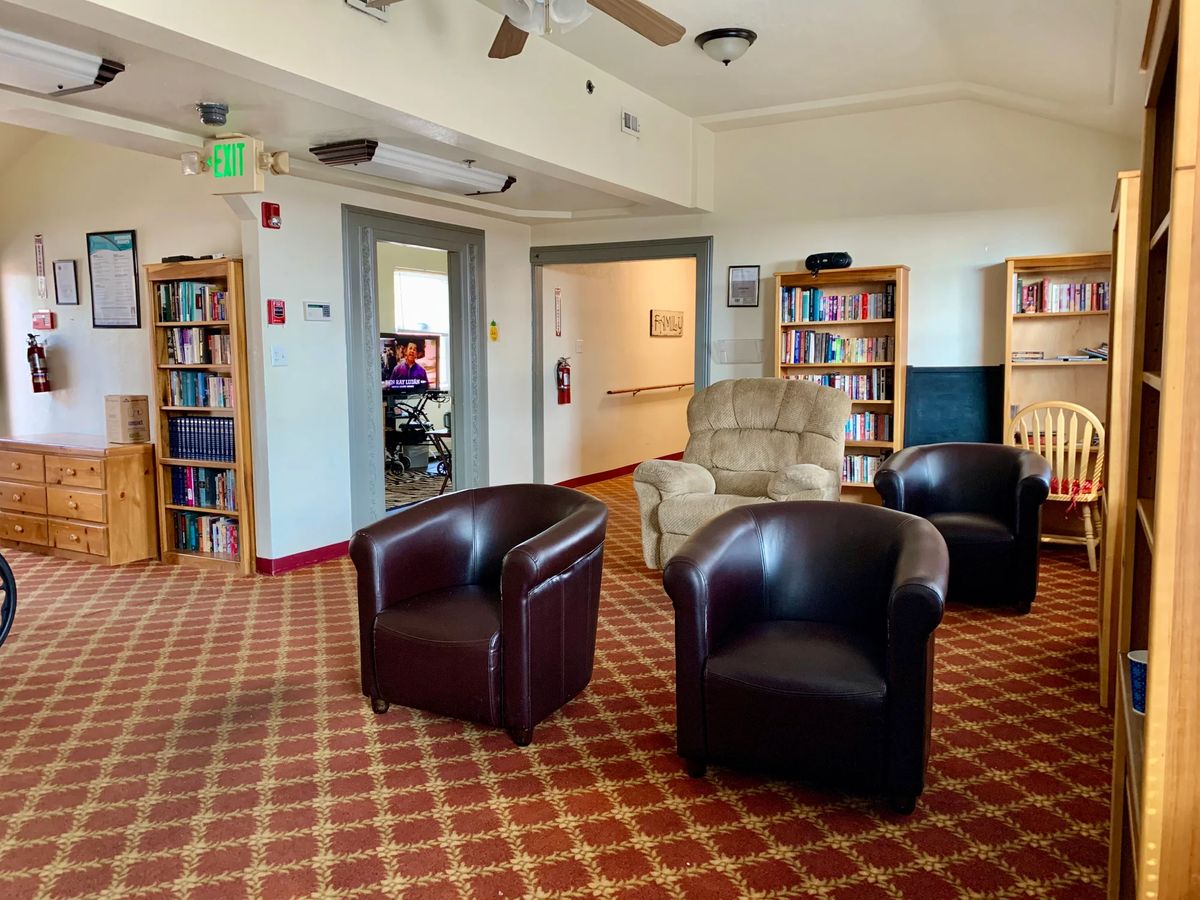 A cozy office space with leather chairs, bookshelves, and a patterned carpet.