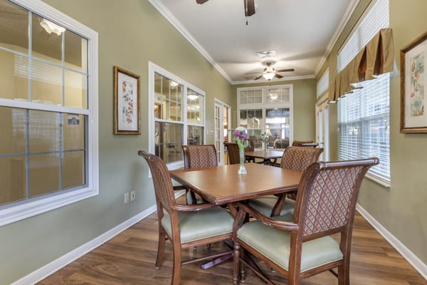 A well-lit dining room with a wooden table, chairs, and ceiling fan.