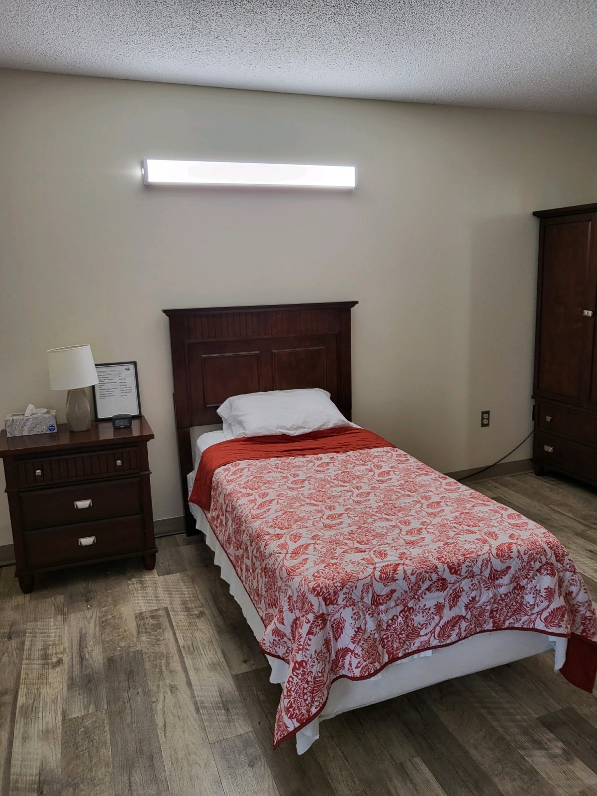 A simple bedroom with a single bed, nightstand, and dresser.