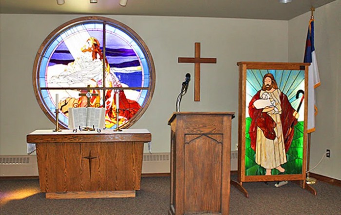 An interior view of a church featuring a pulpit, altar, and stained glass windows.
