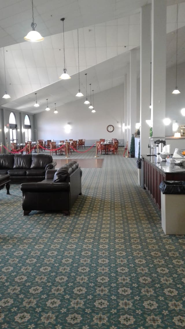 Spacious lounge area with sofas, armchairs, and tables under warm lighting.
