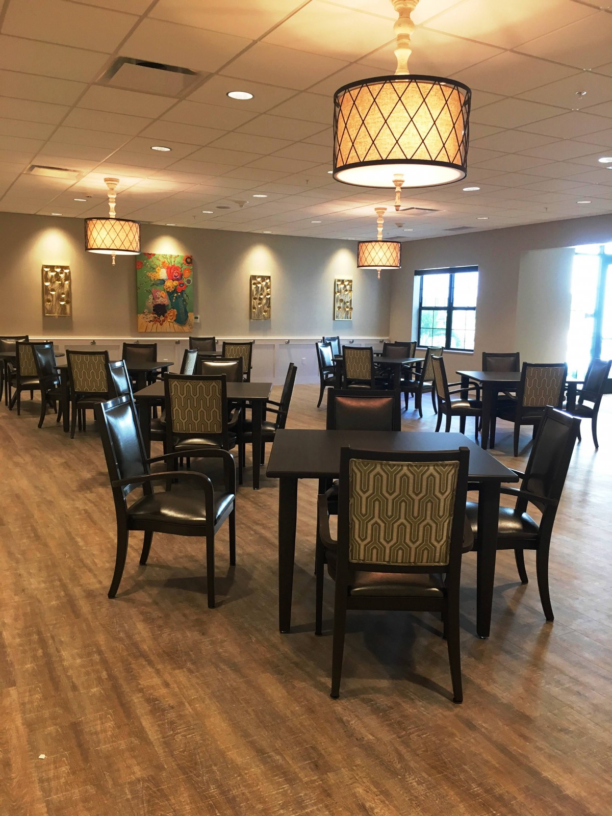A modern dining room with neatly arranged tables and chairs, featuring stylish lighting and decor.