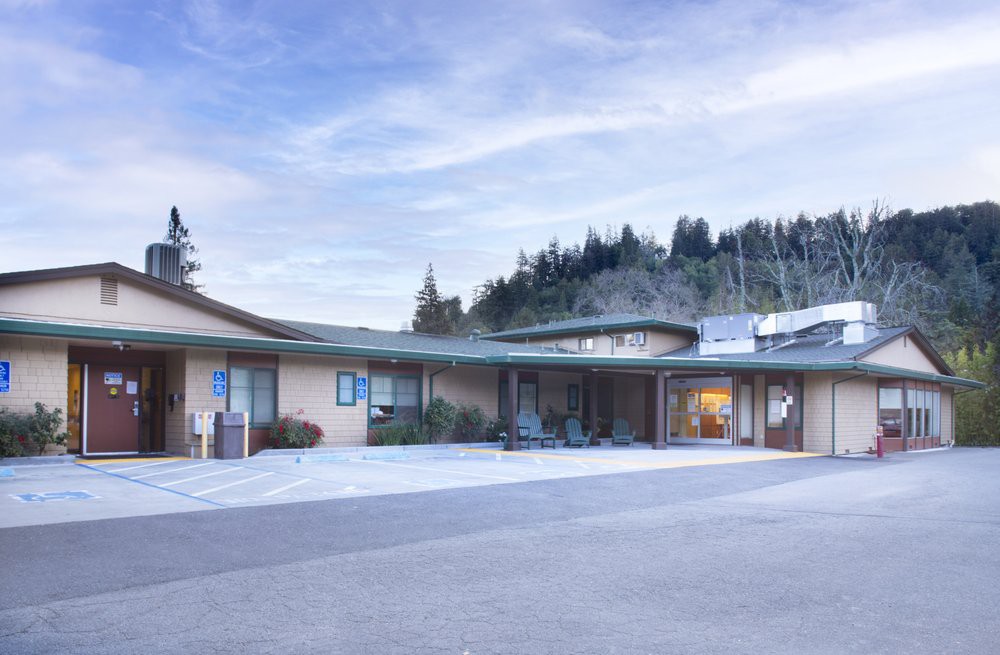 A single-story building surrounded by trees with a clear sky overhead.