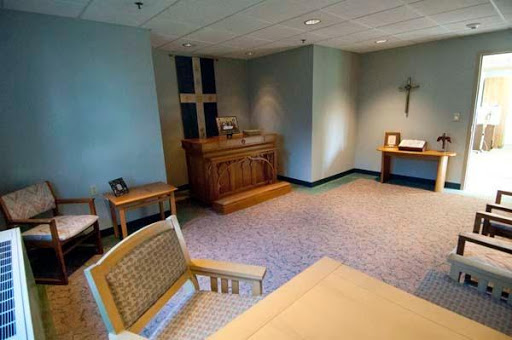 A serene interior of a chapel featuring wooden furnishings and a cross.