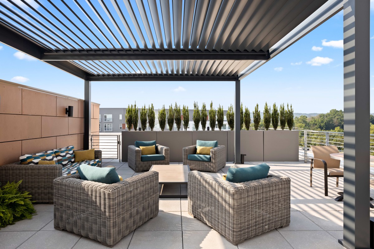 A modern outdoor terrace featuring comfortable patio furniture and a sleek pergola.
