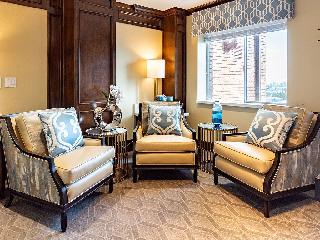 A cozy living room featuring three stylish armchairs, a lamp, and decorative accents.