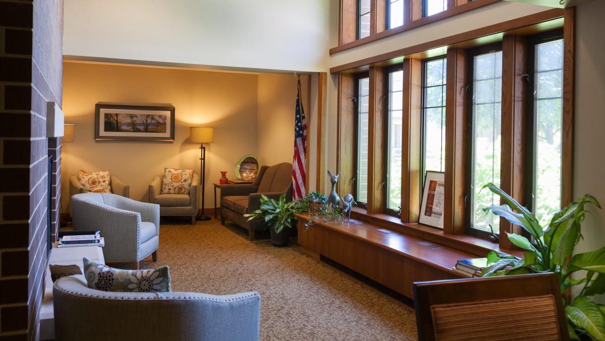 A comfortable office interior with seating, an American flag, and large windows letting in natural light.