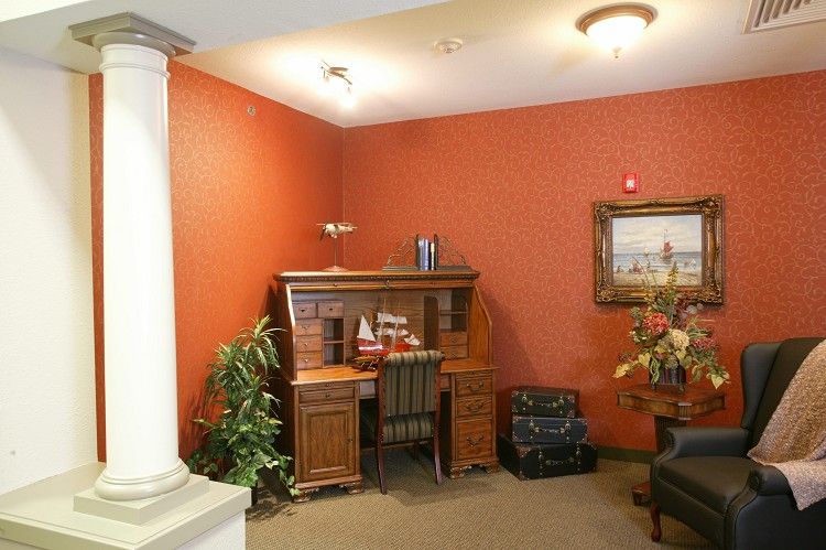 A cozy office corner with a wooden desk, chair, and decorative items.