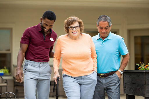 A joyful moment as caregivers assist an elderly woman while walking outdoors.