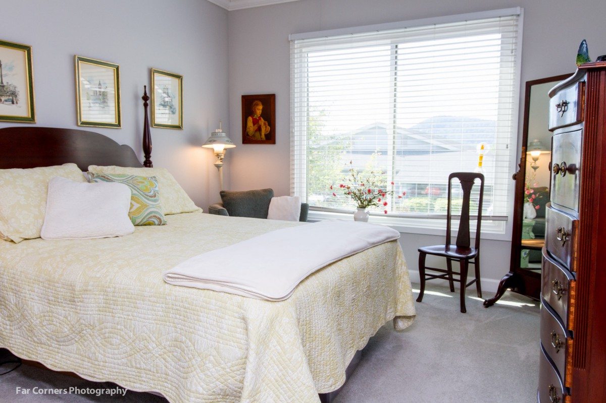 A cozy bedroom with elegant decor and a large window allowing natural light.