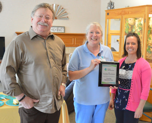 Three individuals proudly holding an award plaque, celebrating recognition in a warm and welcoming setting.