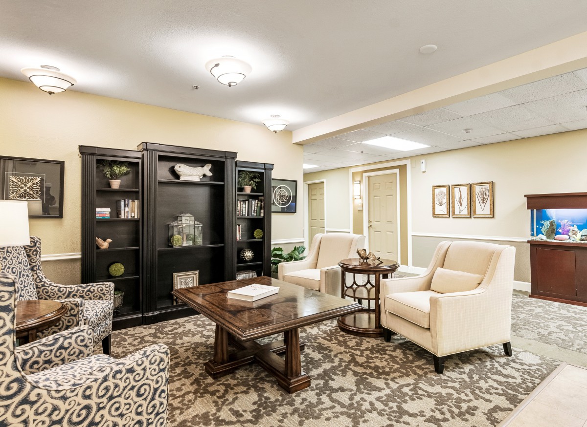 A cozy living room with plush seating, a dark wood bookshelf, and a patterned carpet.
