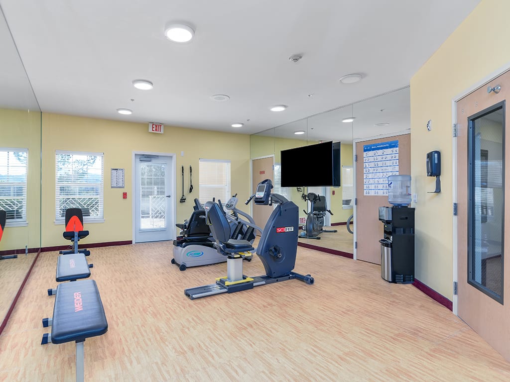 A bright and well-equipped gym with exercise machines, including treadmills and stationary bikes.