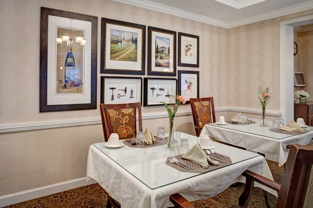 An elegantly decorated dining room with framed artwork and neatly set tables.