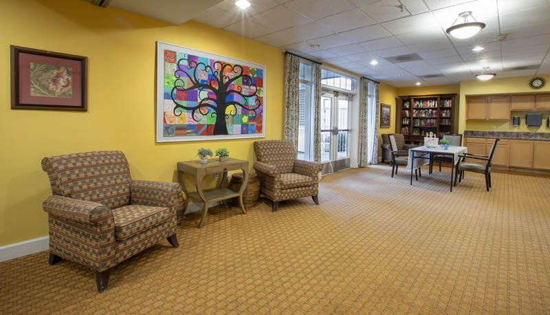 A cozy lobby area with armchairs, colorful artwork on yellow walls, and large windows providing natural light.