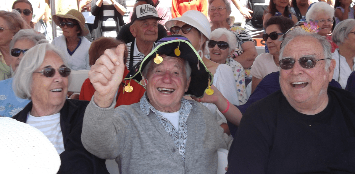 A joyful scene of an elderly man celebrating outdoors among a crowd.
