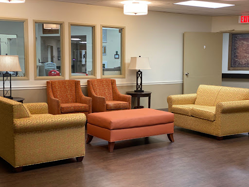 A cozy living room setup featuring colorful seating options including a sofa, two armchairs, and an ottoman.