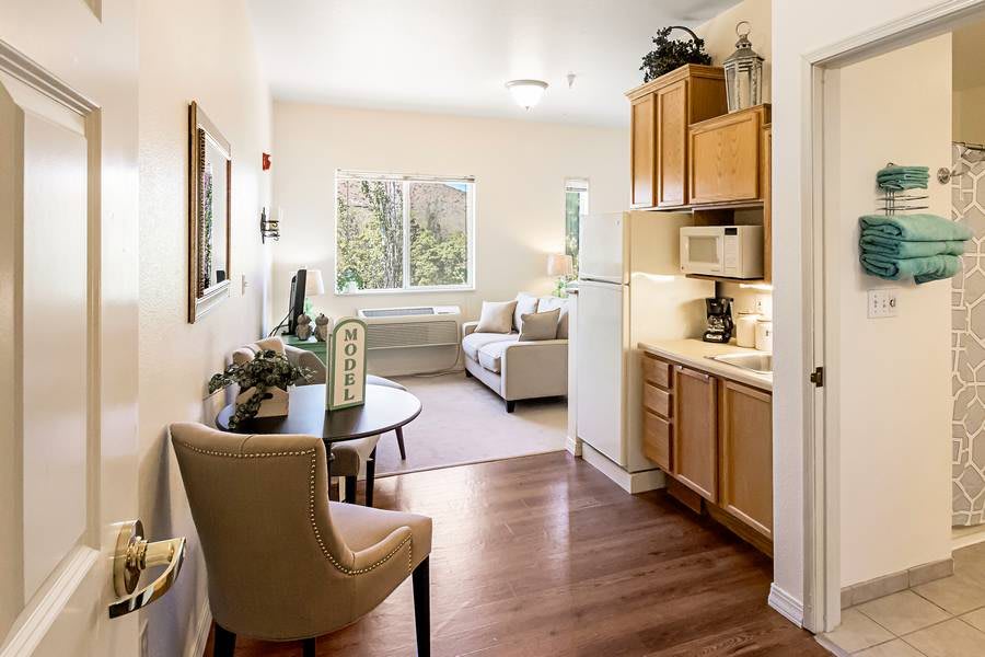 A cozy apartment with a small kitchenette and a living area featuring ample natural light.