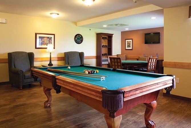 A cozy game room featuring a billiards table and comfortable seating.