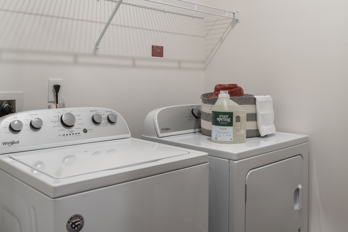 A tidy laundry room with a washing machine, dryer, and essential supplies.