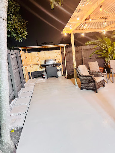 A cozy outdoor patio setup featuring comfortable seating and a grill, illuminated by soft evening lights.