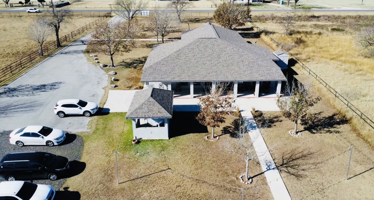 Aerial view of a house with a spacious yard and driveway.