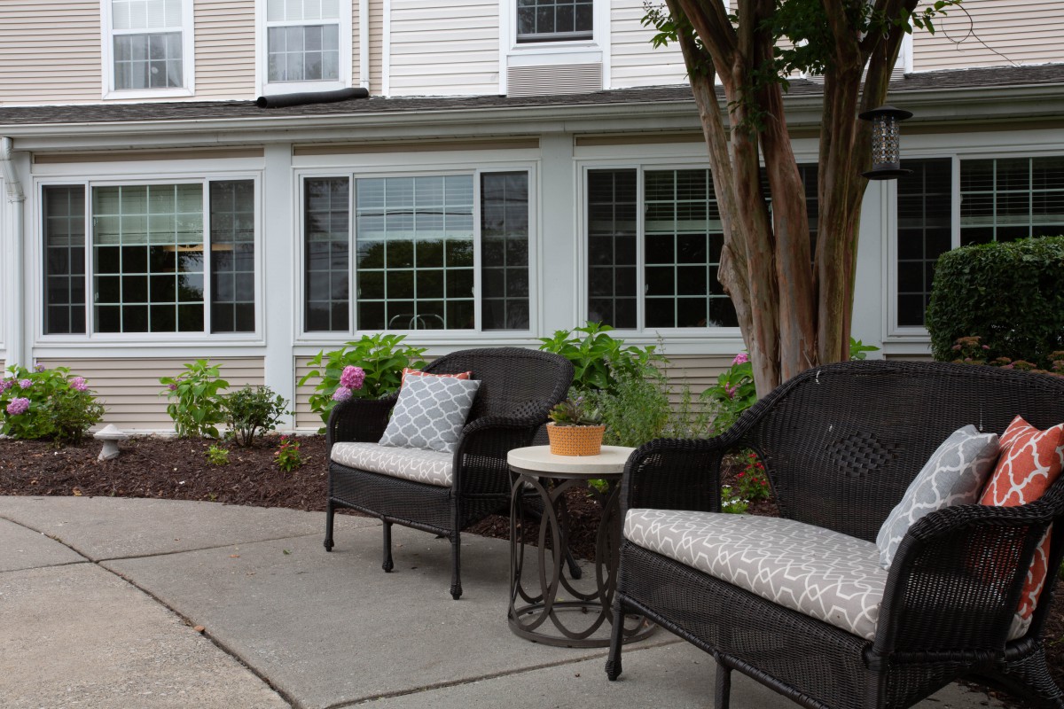 A cozy outdoor patio area with chairs, a table, and surrounding greenery.