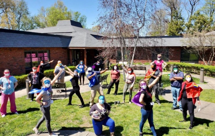 A group of people posing outdoors in masks and costumes, practicing social distancing.